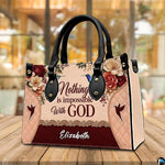 Three-quarter perspective view of the hummingbird floral handbag resting on an outdoor wooden table.