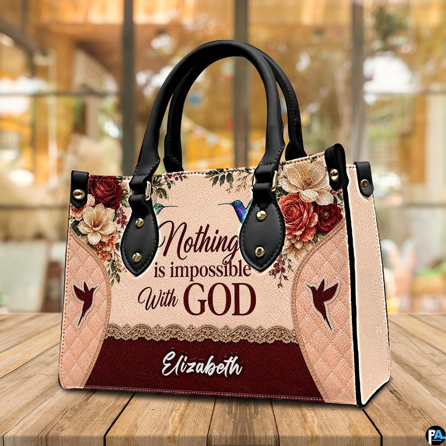 Three-quarter perspective view of the hummingbird floral handbag resting on an outdoor wooden table.