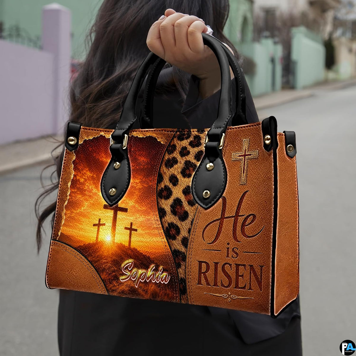 Woman carrying the sunrise cross faith handbag outdoors on a paved street.