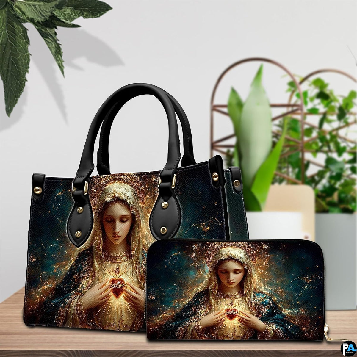 Handbag and companion wallet with Virgin Mary devotional art displayed beside indoor greenery.