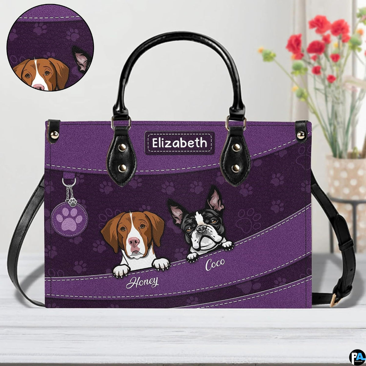 Close-up perspective of illustrated puppy faces, paw print pattern, and decorative badge on handbag.