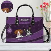 Close-up perspective of illustrated puppy faces, paw print pattern, and decorative badge on handbag.