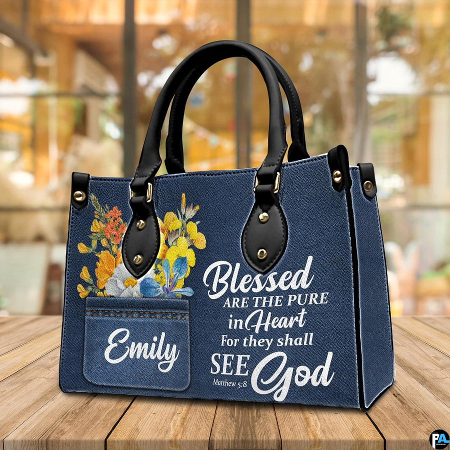 Tabletop perspective of scripture denim handbag standing upright on wooden surface