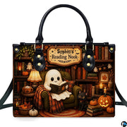 Front view of structured satchel displaying ghost in armchair with black kitten inside an autumn library.
