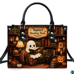 Front view of structured satchel displaying ghost in armchair with black kitten inside an autumn library.