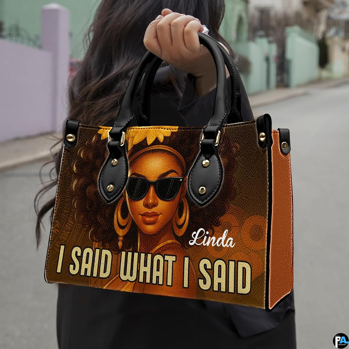 Urban outdoor perspective of model holding the afro queen statement handbag by upper handles.
