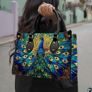 Woman carrying blue green peacock artwork handbag by top handles