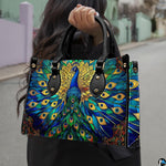 Woman carrying blue green peacock artwork handbag by top handles