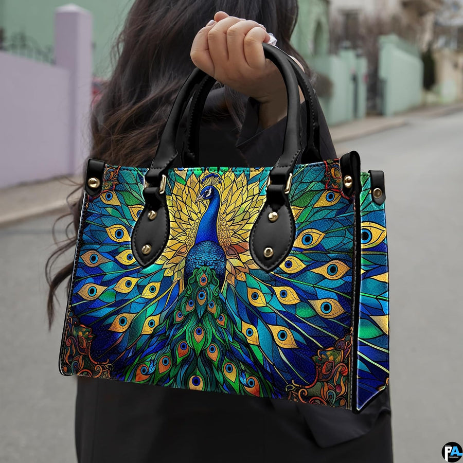 Woman carrying blue green peacock artwork handbag by top handles