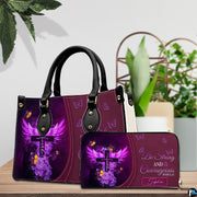 Purple winged cross handbag and matching wallet displayed on a wooden surface beside green foliage.