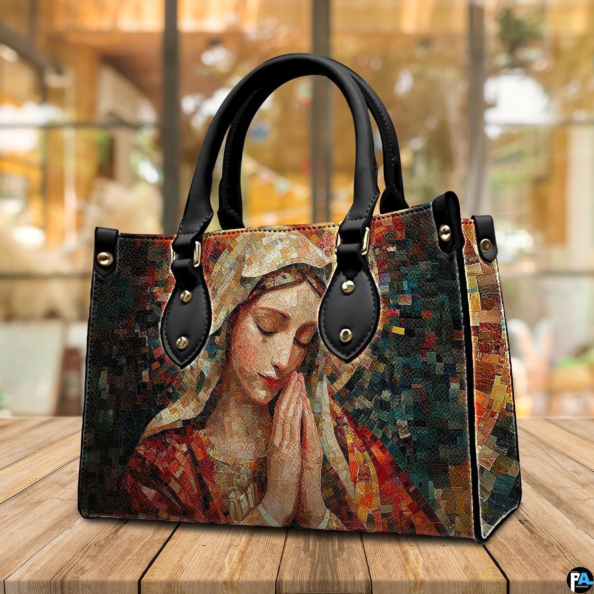 Terracotta mosaic Praying Virgin Mary handbag displayed in three-quarter view on cafe table.