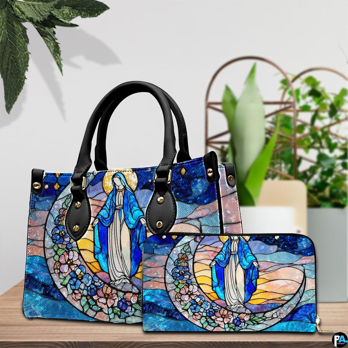 Handbag and matching zippered wallet with stained glass Virgin Mary design displayed on wooden table.