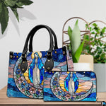Handbag and matching zippered wallet with stained glass Virgin Mary design displayed on wooden table.