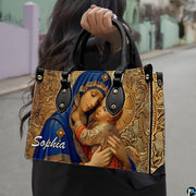Model carrying royal blue mantle Virgin Mary and Child devotional handbag outdoors