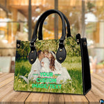 Front view of sunny meadow family portrait handbag standing upright on wooden tabletop.