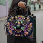 Model holding mandala hummingbird handbag outdoors displaying rich ornamental avian artwork.