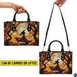 Stained glass Halloween witch handbag displayed on white table beside floral bouquet.