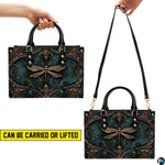 Top view of gold dragonfly handbag showing zippered top closure and dual structured handles