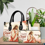 Good Shepherd handbag and wallet displayed on wooden table beside potted plant.