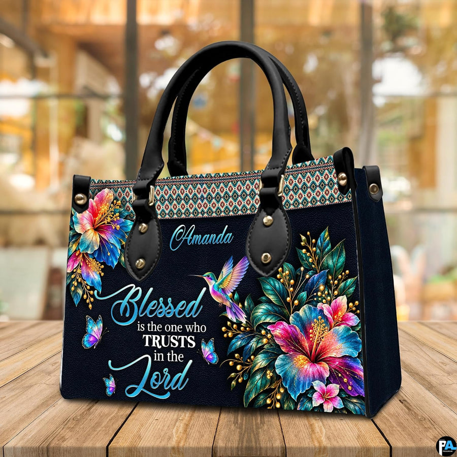 Hummingbird handbag displayed on wooden tabletop in front of sunlit cafe window.