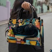 Sleeping black cat painting held outdoors along a sunny city street.