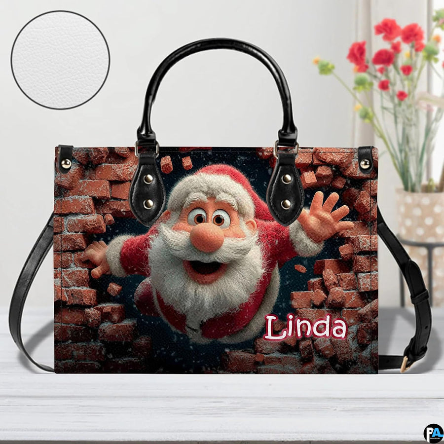 Holiday Santa themed handbag displayed on white surface beside floral arrangement.