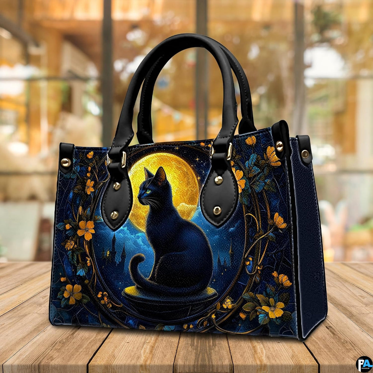 Cafe setting presenting gothic black cat artwork resting on a wooden tabletop near windows.