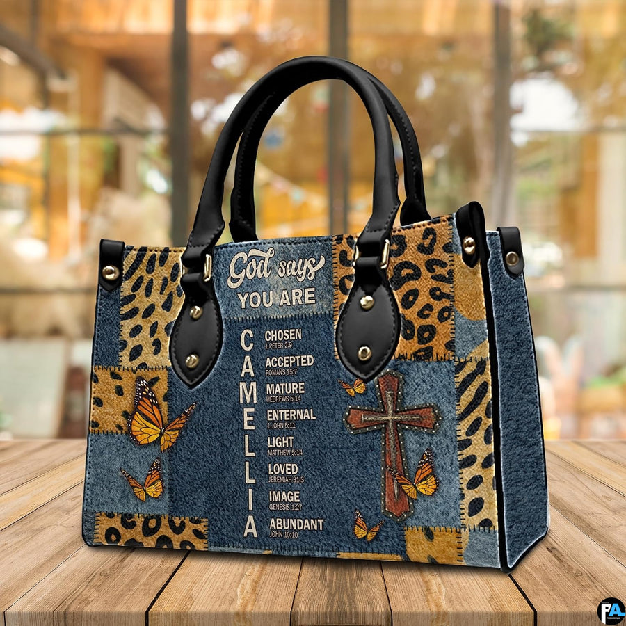 Tabletop perspective of Christian cross butterfly handbag standing upright on wooden surface