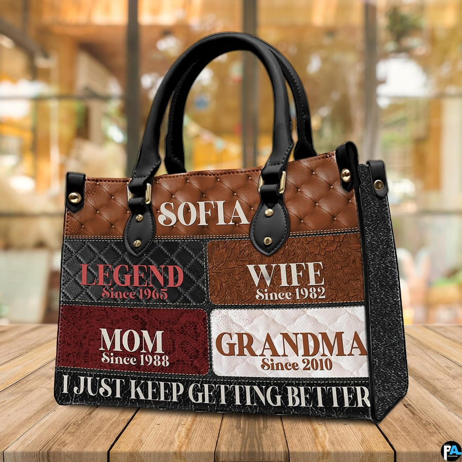 Side view of patchwork handbag displaying dark handle attachments and textured grid artwork.