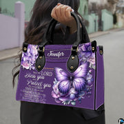 Detailed angle view of shimmering violet winged butterfly and lavender floral clusters on handbag.