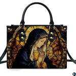 Front perspective of handbag featuring praying Virgin Mary within an amber stained glass arch
