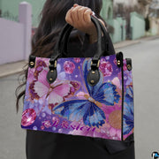 Side profile view of the butterfly handbag showing structured shape and black handles.