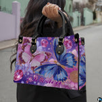 Side profile view of the butterfly handbag showing structured shape and black handles.