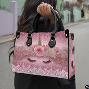 Side profile of pastel unicorn handbag showing structured silhouette and black carrying handles.