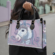 Side profile of unicorn handbag showing structured silhouette and black carrying handles.