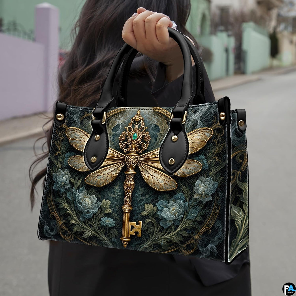 Three-quarter view of dragonfly key purse showing structured shape, handles, and gold accents