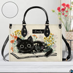 Close-up front view of black kitten on open book artwork on structured tote handbag