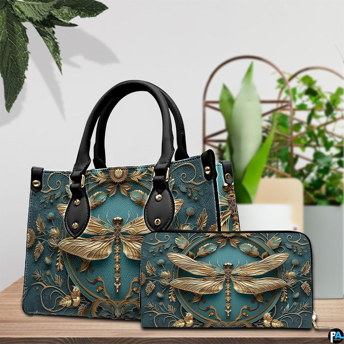 Tabletop lifestyle presentation of gold dragonfly handbag and matching wallet with potted plants