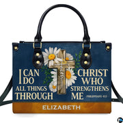 Frontal view of navy handbag showcasing a wooden cross with white daisies, green leaves, and devotional verse lettering.