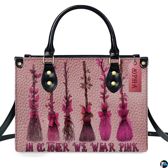 Witch broom art accessory displaying rustic sweepers decorated in pink ribbons against blush paneling.