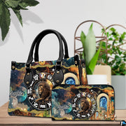 Celestial Lion Satchel Handbag and continental wallet set shown on a wooden table beside greenery.