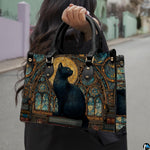 Black cat full moon gothic cathedral artwork held outdoors along a sunlit city walkway.