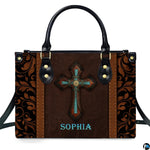 Western handbag featuring an ornate cross with turquoise stone inlay, studded borders, and carved scrollwork.