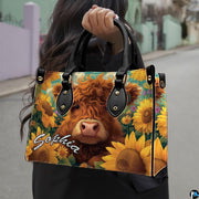 Outdoor street view of ginger Highland cow in sunflower field design carried by hand