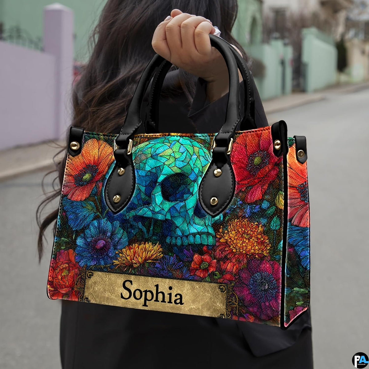 Stained glass skull handbag carried outdoors by top handle along residential street.