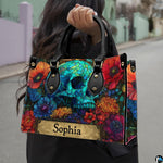 Stained glass skull handbag carried outdoors by top handle along residential street.