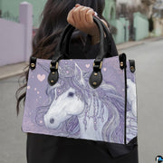 Side profile of crowned unicorn handbag showing structured silhouette and black carrying handles.