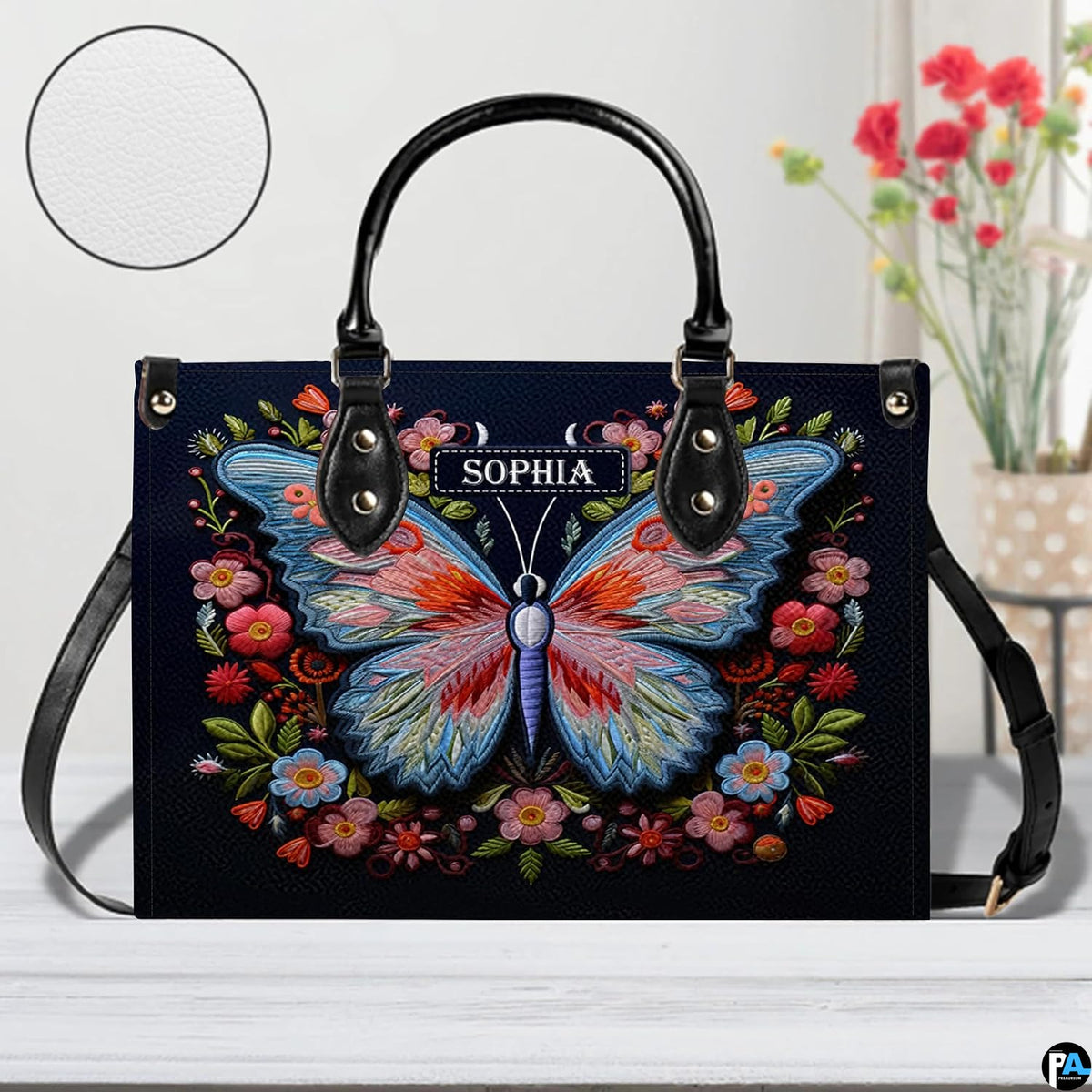 Front perspective of the embroidered butterfly handbag resting on a white tabletop.