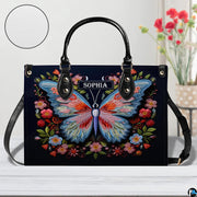 Front perspective of the embroidered butterfly handbag resting on a white tabletop.