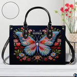 Front perspective of the embroidered butterfly handbag resting on a white tabletop.